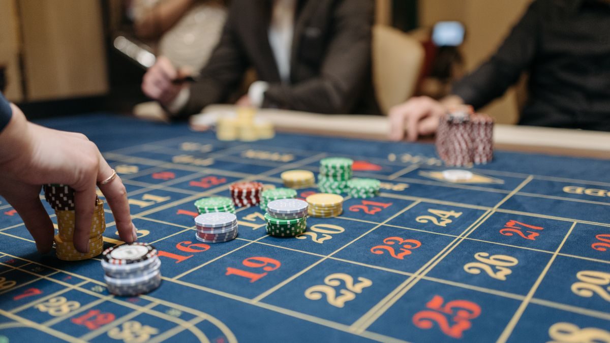 Tangan pemain meletakkan chip di meja roulette, melambangkan pengambilan keputusan yang cermat